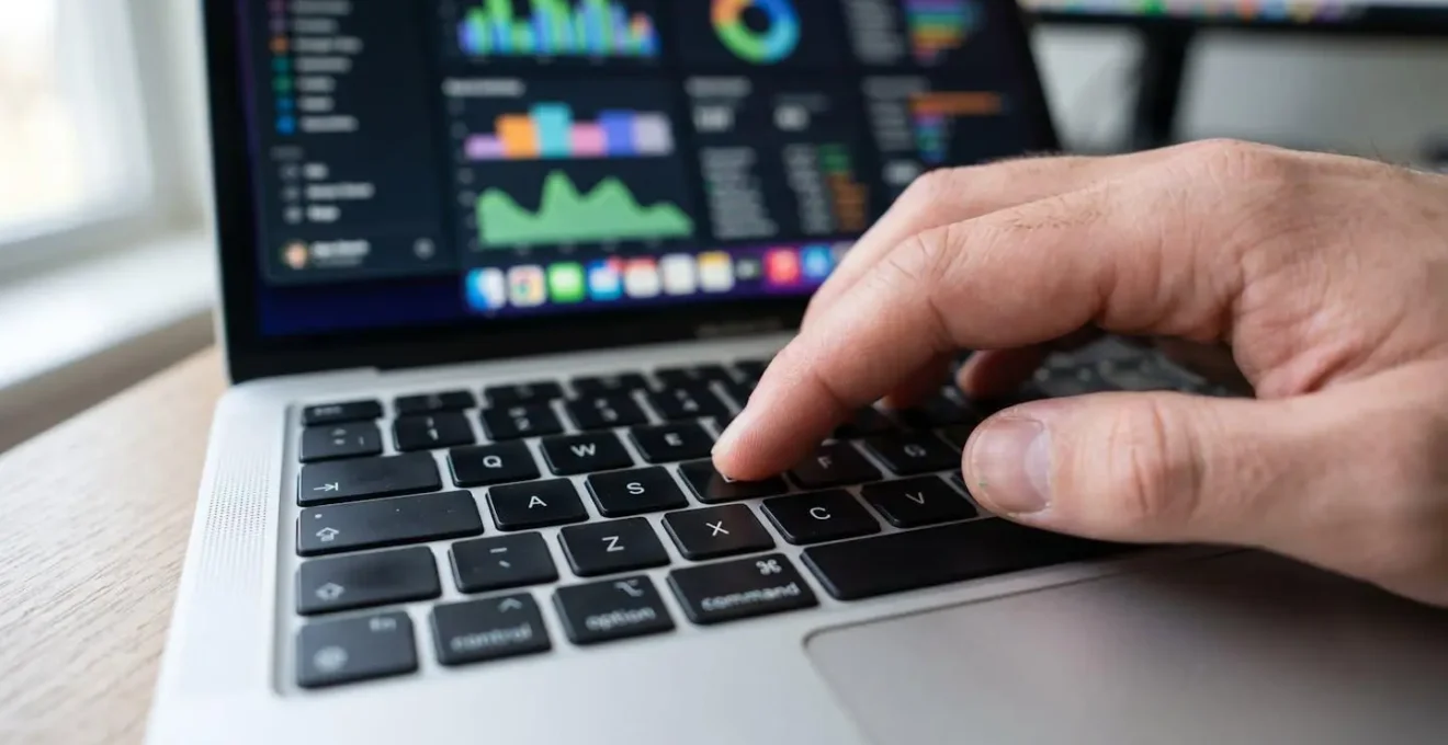 Gros plan sur des mains tapant sur le clavier d'un ordinateur portable moderne avec des graphiques colorés flous en arrière-plan